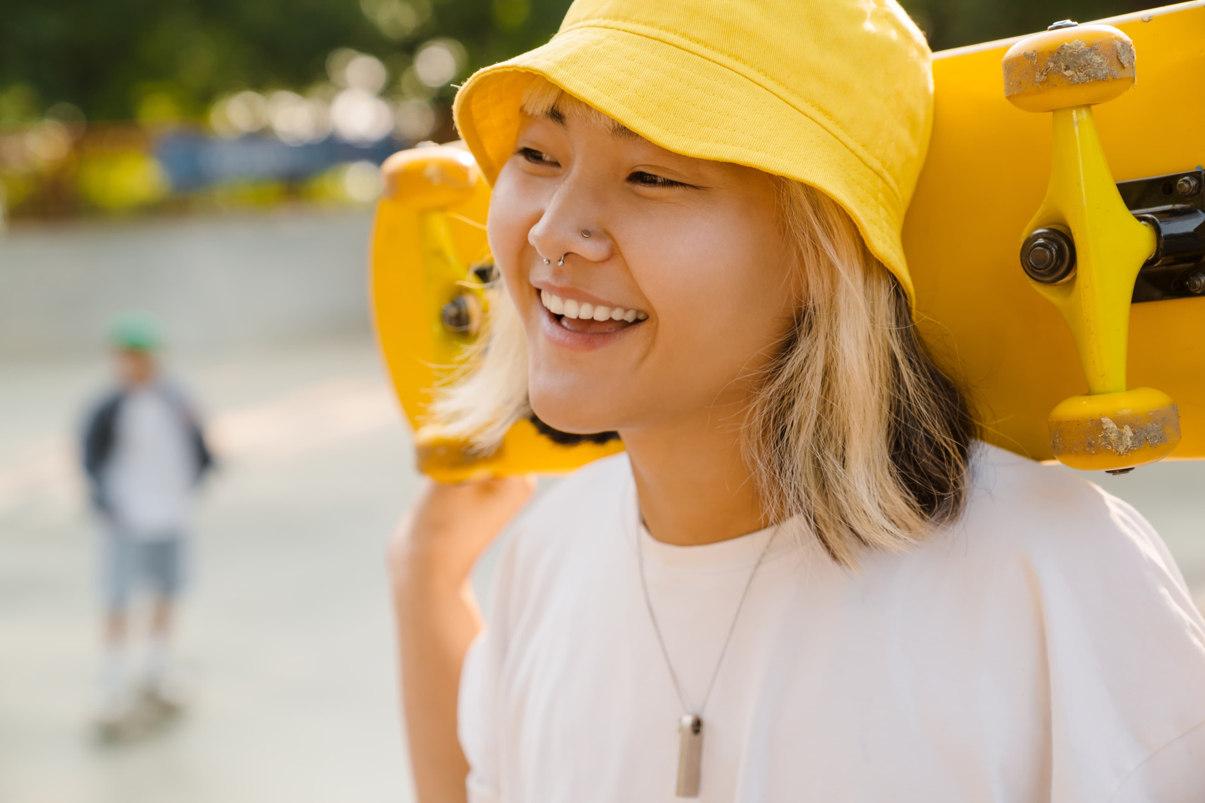 Asian girl wearing hat holding skateboard